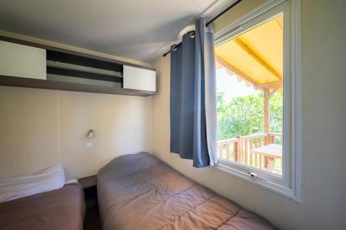 une chambre avec un lit et une fenêtre avec un balcon dans l'établissement Mobil home 6 personnes piscine parc du Pilat, à Saint-Appolinard