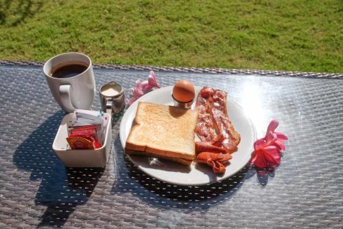 un piatto di prodotti per la colazione e una tazza di caffè di Fat Yogi Cottages a Kuta