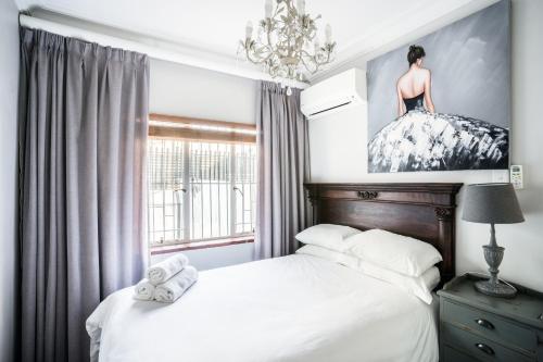 1 dormitorio con 1 cama y una pintura en la pared en Avemore Wag n Bietjie No 1 en Stellenbosch