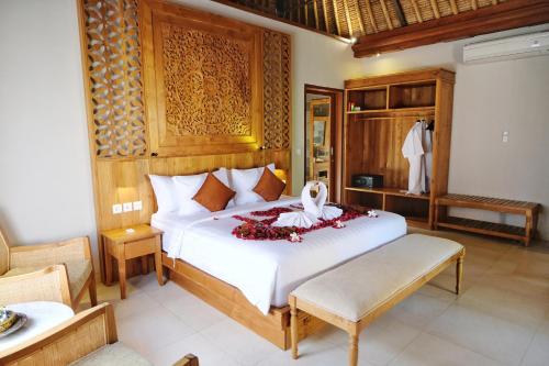 a bedroom with a large white bed with flowers on it at Puri Andong Villa in Ubud