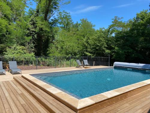 a swimming pool with two chairs and a wooden deck at Les Volets Violets in Salles