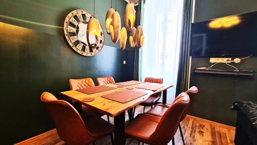 comedor con mesa, sillas y reloj en Vienna CityApartments - Premium 6, en Viena