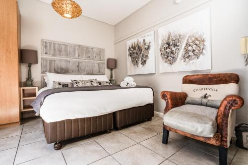 a bedroom with a large bed and a chair at Avemore Eikehof No 24 in Stellenbosch