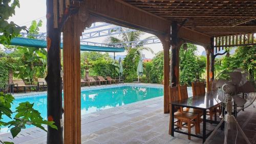 un patio con una mesa y una piscina en Tam Coc Amanda Villas, en Ninh Binh