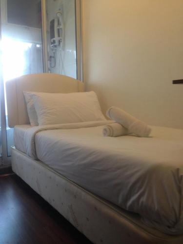 a bed with white sheets and pillows in a room at Woodpecker Lodge, Kuching in Kuching