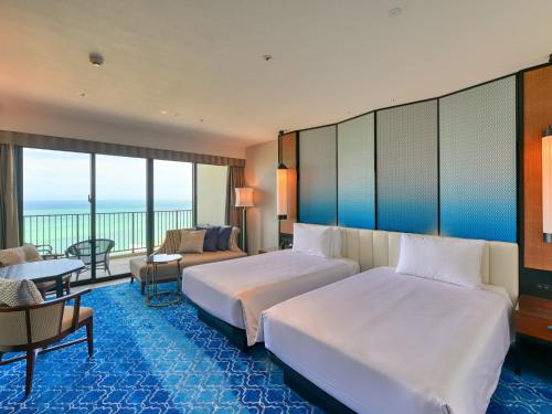 a hotel room with two beds and a couch at Ryukyu Hotel & Resort Nashiro Beach in Itoman