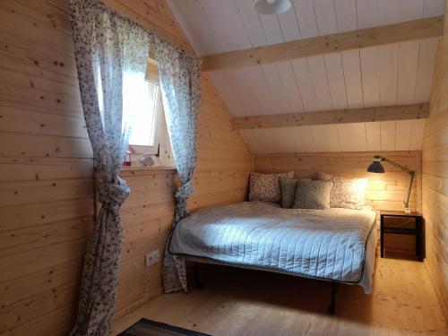 a bedroom in a log cabin with a bed and a window at Na Miedzy in Dźwierzuty