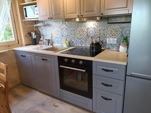 a kitchen with a stove and a sink at Na Miedzy in Dźwierzuty