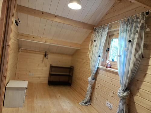 an inside view of a log cabin with a bed and curtains at Na Miedzy in Dźwierzuty