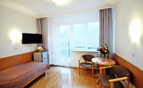 une chambre d'hôtel avec un lit, une table et une fenêtre dans l'établissement SP ZOZ Sanatorium Uzdrowiskowe MSWiA w Kołobrzegu, à Kołobrzeg