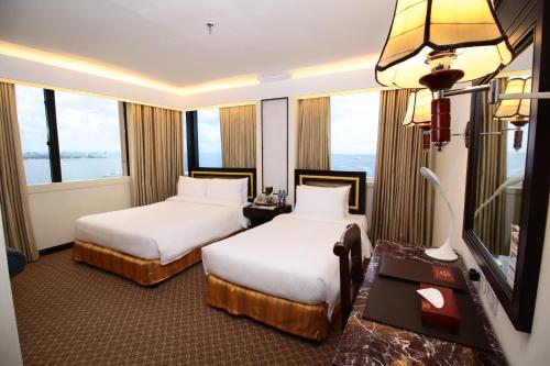 马尼拉Bayview Park Hotel Manila的带窗户的酒店客房内的两张床
