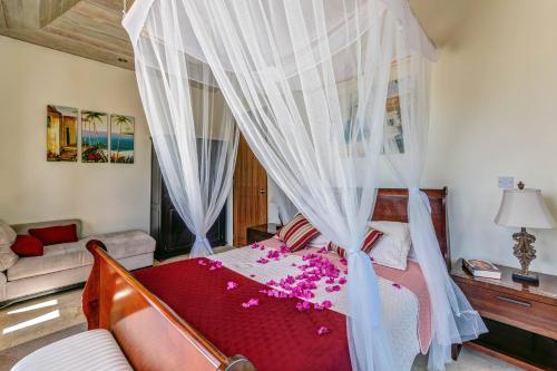 a bedroom with a canopy bed with pink flowers on it at Sadewa Villa in Port Elizabeth