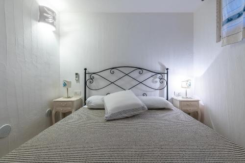 a white bedroom with a bed with a black headboard at Casa Vacanza Il Bouganville in Villasimius