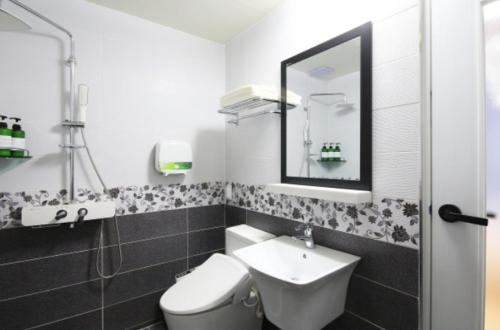 a bathroom with a sink and a toilet and a mirror at Java Hotel in Gwangyang