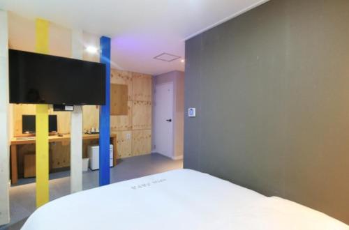 a bedroom with a bed and a tv on a wall at Java Hotel in Gwangyang