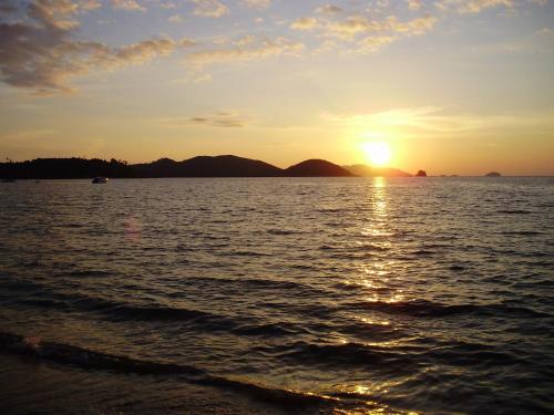 a sunset over the water with mountains in the background at Happy Days Resort in Ko Mak