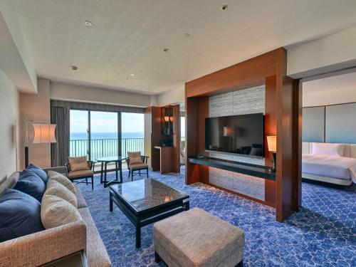 a hotel room with a couch and a bed and a television at Ryukyu Hotel & Resort Nashiro Beach in Itoman