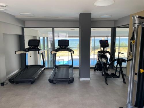 a gym with treadmills and ellipticals in a room with windows at Apartamenty The View Hevenia in Rewal