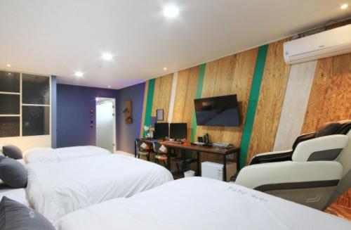 a room with two beds and a desk with a computer at Java Hotel in Gwangyang