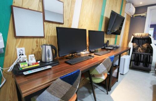 a desk with three computer monitors on top of it at Java Hotel in Gwangyang