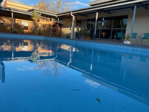 a swimming pool with blue water in front of a house at Gateway Motor Inn in Narrandera