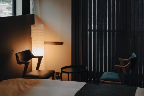 a hotel room with a bed and chairs and a window at 河内家 in Fujikawaguchiko