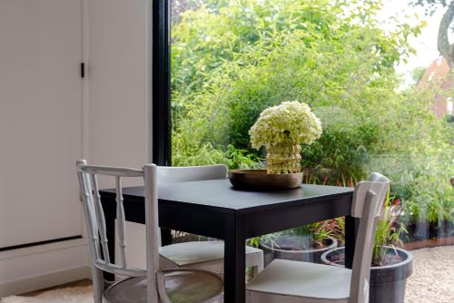 a black table and chair with a vase of flowers at #1Leafy Place in Bentveld