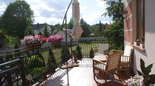 a balcony with chairs and an umbrella and flowers at Noclegi Pod Różą in Krasnobród