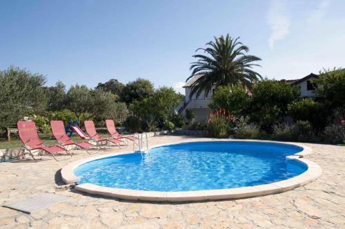a small swimming pool with chairs and a palm tree at Apartment Mundanije 5072b in Rab