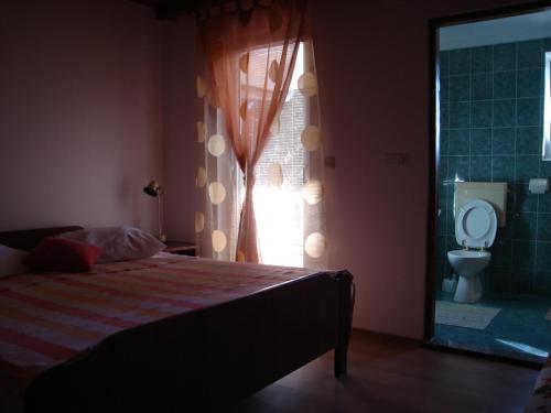 een slaapkamer met een bed en een raam met een toilet bij Apartment Kampor 5014b in Kampor