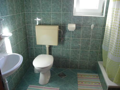 een groene betegelde badkamer met een toilet en een wastafel bij Apartment Kampor 5014b in Kampor