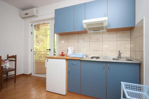 una cucina con armadi blu e lavandino di Apartment Zivogosce - Porat 6700a a Igrane