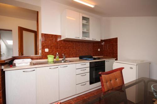 a kitchen with white cabinets and a sink and a stove at Apartment Gradac 6819a in Gradac