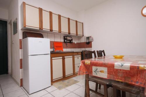 kuchnia ze stołem i białą lodówką w obiekcie Apartment Povljana 6502a w mieście Povljana