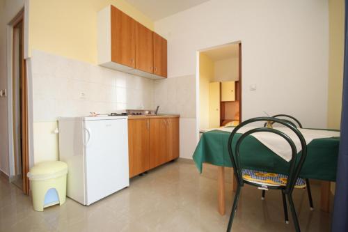 a small kitchen with a table and a white refrigerator at Apartment Starigrad 6587b in Starigrad-Paklenica