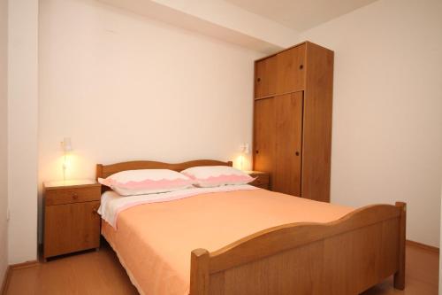 ein Schlafzimmer mit einem Holzbett mit zwei Kissen in der Unterkunft Apartment Tucepi 6857a in Tučepi