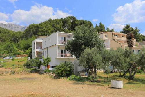 a building in the middle of a field with trees at Apartment Tucepi 6695a in Tučepi