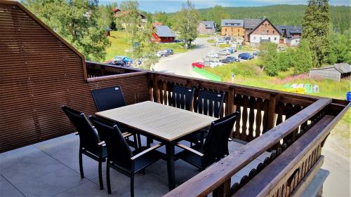 a table and chairs on a balcony with a view at Wellness apartmán Kvilda in Kvilda