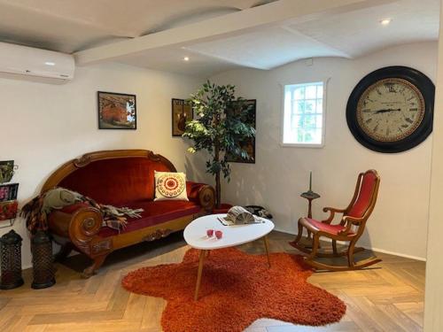 a living room with a couch and a clock on the wall at Guldforhoved B&B in Bording Kirkeby