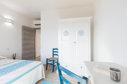 a white bedroom with a bed and a chair at Sa Domm'e Galleria in Baunei