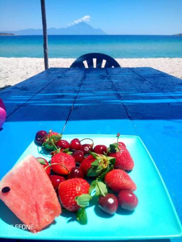 a plate of fruit on a table on the beach at Malama Rooms in Sikia