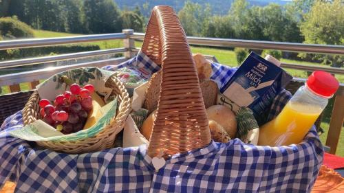 a basket of food on a table with a bottle of orange juice at Chalets zum Latschen in Mauth