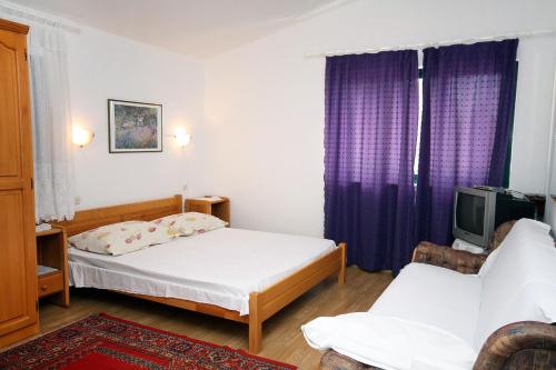a bedroom with two beds and a tv and purple curtains at Studio Drvenik Gornja vala 4890e in Drvenik
