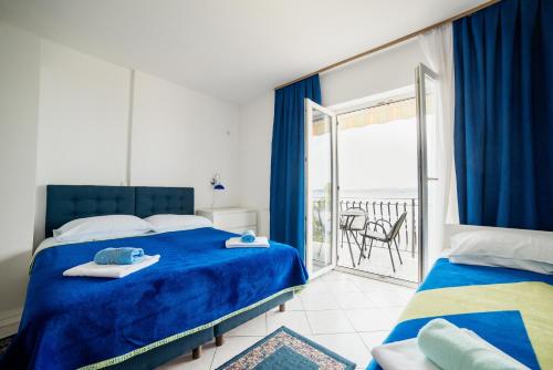 a bedroom with a blue bed and a balcony at Studio Selce 5206d in Selce