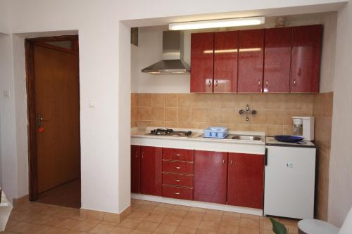 una cocina con armarios rojos y fregadero en Studio Tisno 5091a, en Tisno