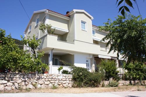 a white house with a stone wall at Studio Banjol 5071a in Rab