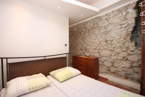 a bedroom with two beds and a stone wall at Studio Gradac 6661a in Gradac