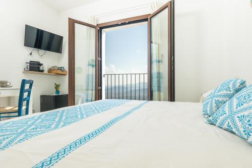 a bedroom with a large bed with a balcony at Sa Domm'e Galleria in Baunei
