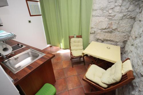 una cucina con lavandino, tavolo e tavolo di Studio Gradac 6661a a Gradac (Grado)