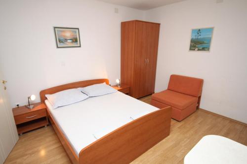um pequeno quarto com uma cama e uma cadeira em Studio Makarska 6696a em Makarska